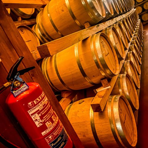 Extintor en bodega con barricas de madera